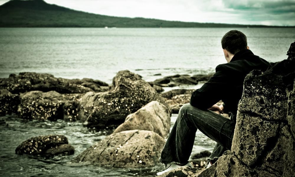 Photo of adolescent sitting near the water